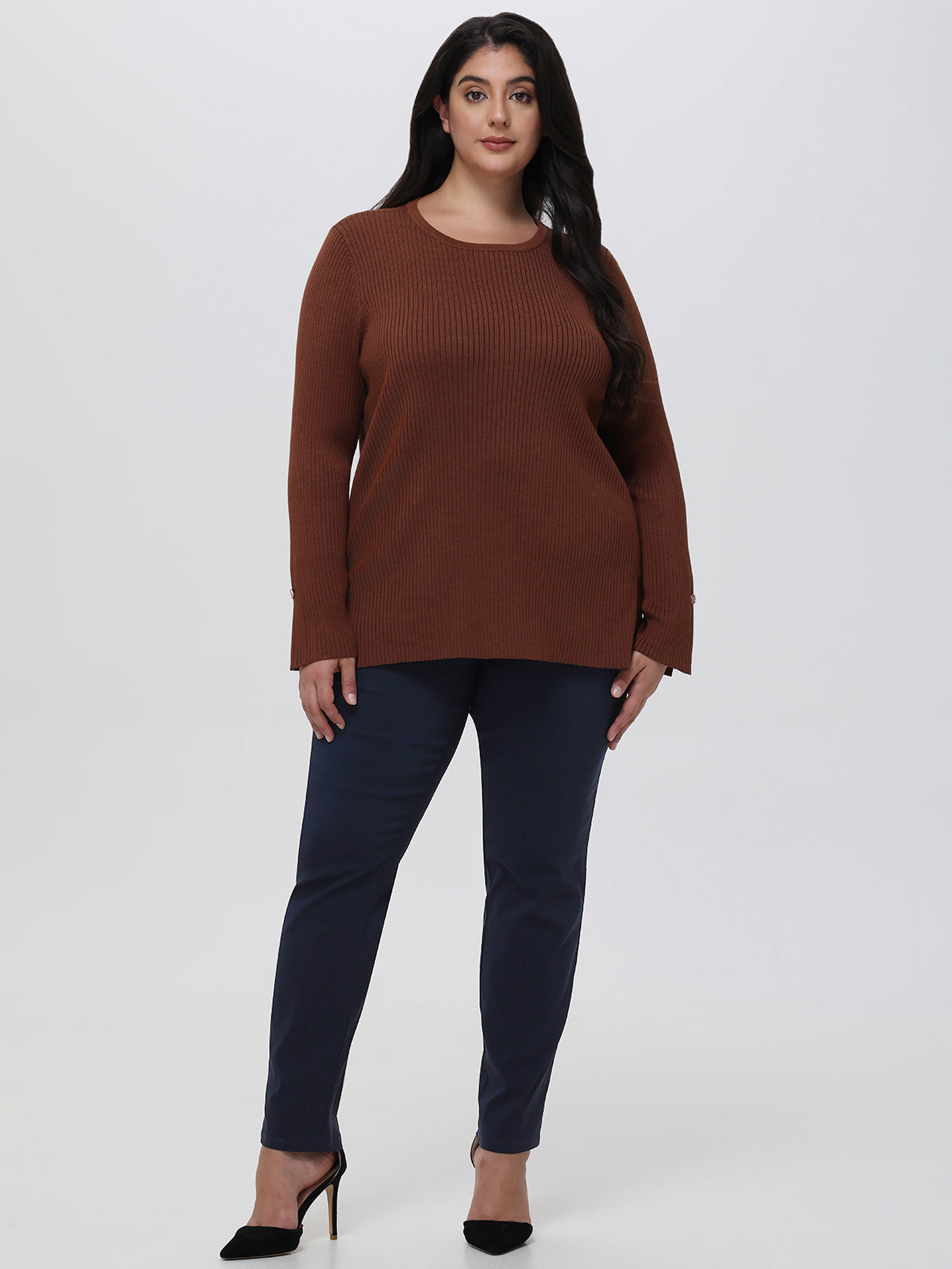 Woman wearing a brown sweater and dark blue pants on a white background