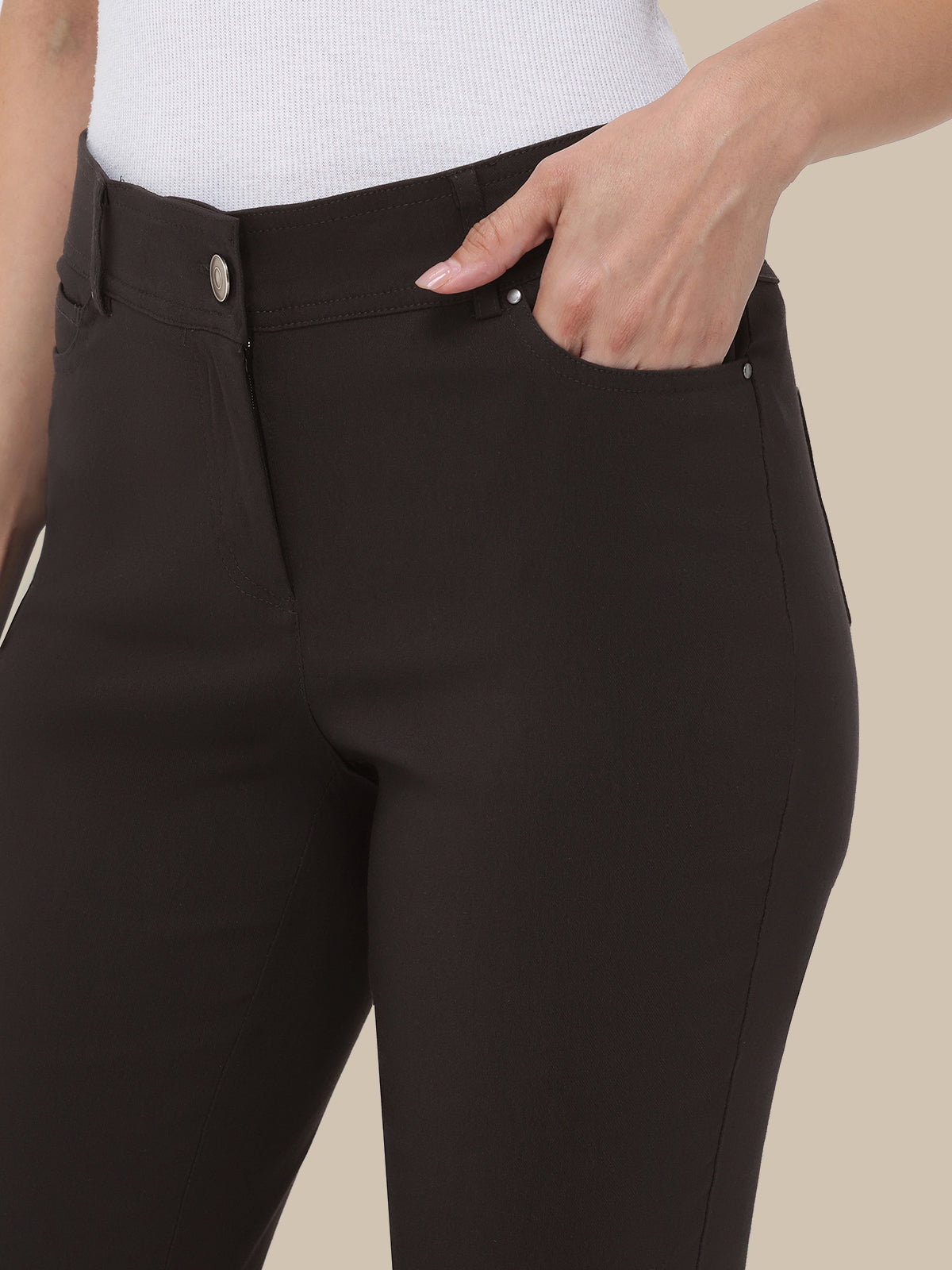 Black pants with white buttons on a beige background