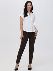 Woman wearing a white blouse and brown pants on a white background