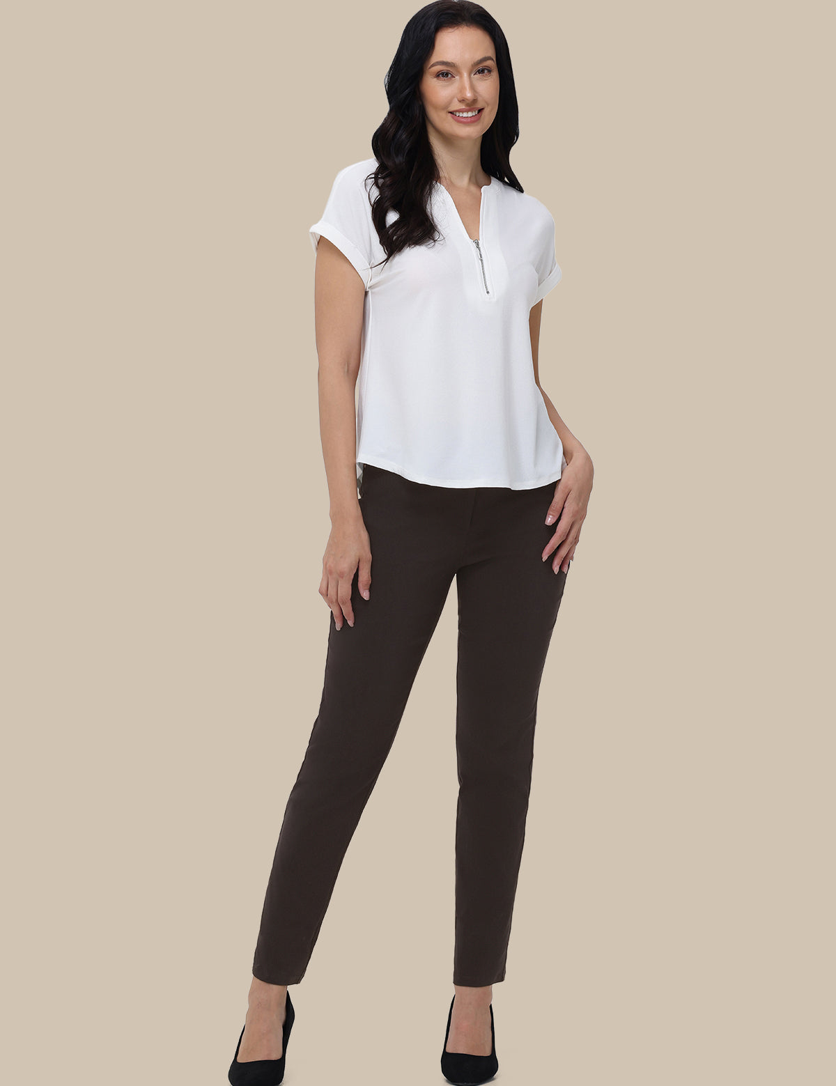 Woman wearing a white blouse and black pants on a beige background