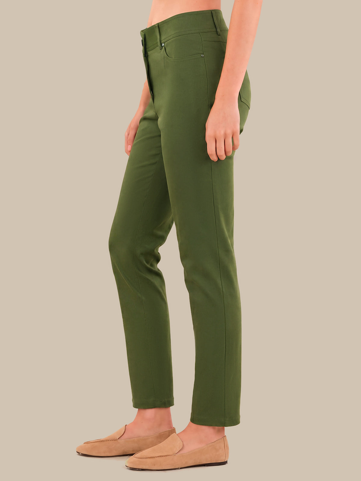 A model wearing olive green slim-fit trousers and tan loafers, shown from the waist down against a solid beige background.