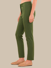 A model wearing olive green slim-fit trousers and tan loafers, shown from the waist down against a solid beige background.
