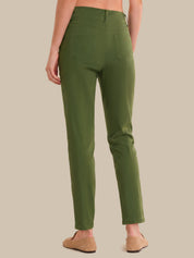 A person shown from the back wearing olive green slim-fit pants and tan slip-on shoes against a plain beige studio background.