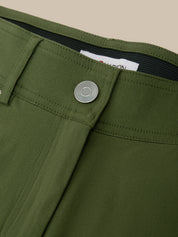 Close-up of olive green trousers showing the waistband, button closure, belt loops, and inner label on a plain beige background.