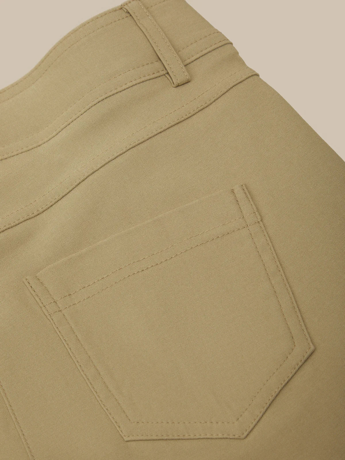 Close-up of beige pants with a pocket on a beige background