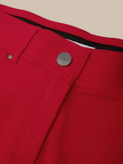 Close-up of a red pants pocket with a button and zipper on a beige background