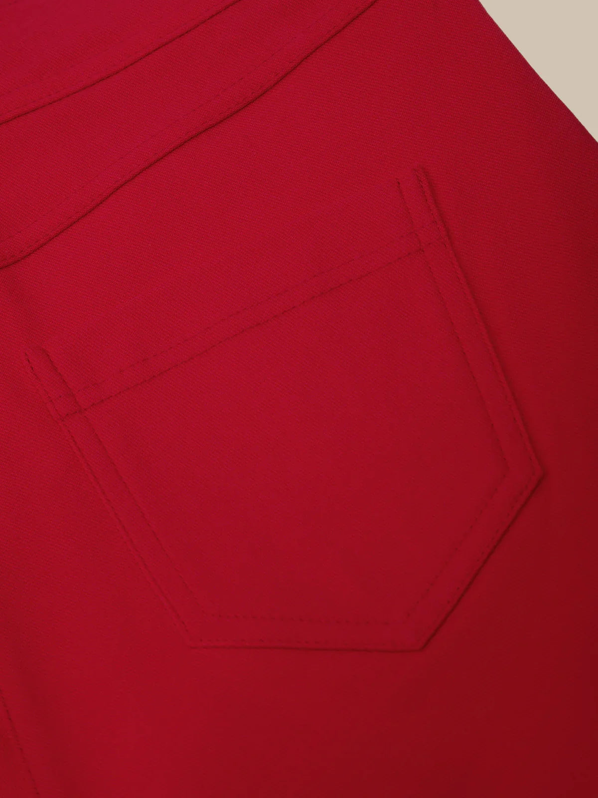 Close-up of a red fabric with a pocket design on a beige background