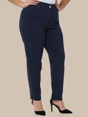 A model wearing navy blue slim-fit pants with a silver button closure, paired with black high heels, shown from the waist down against a solid beige background.