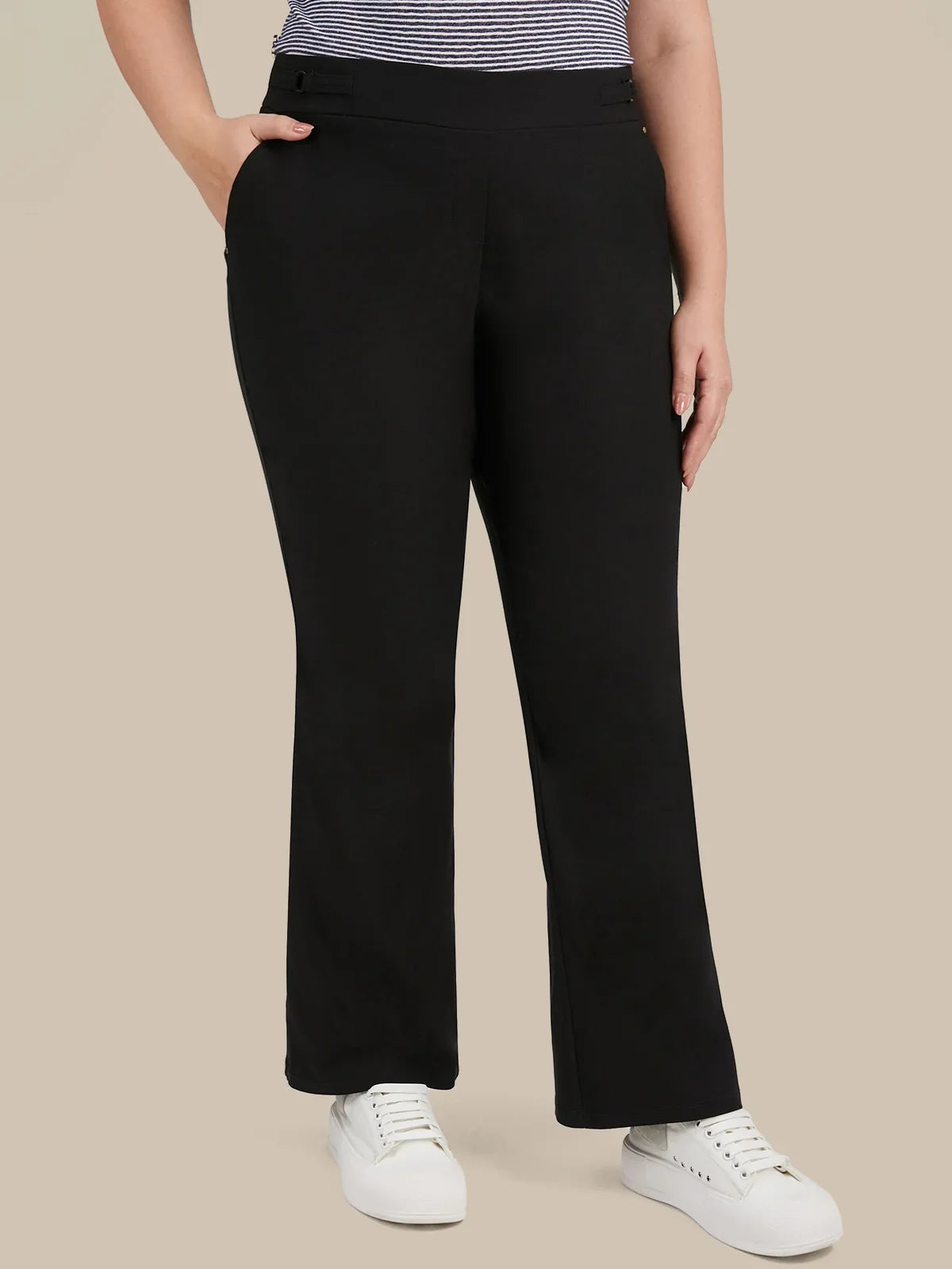 A model wearing black wide-leg cropped pants with a striped top and white sneakers, shown from the waist down against a solid beige background.