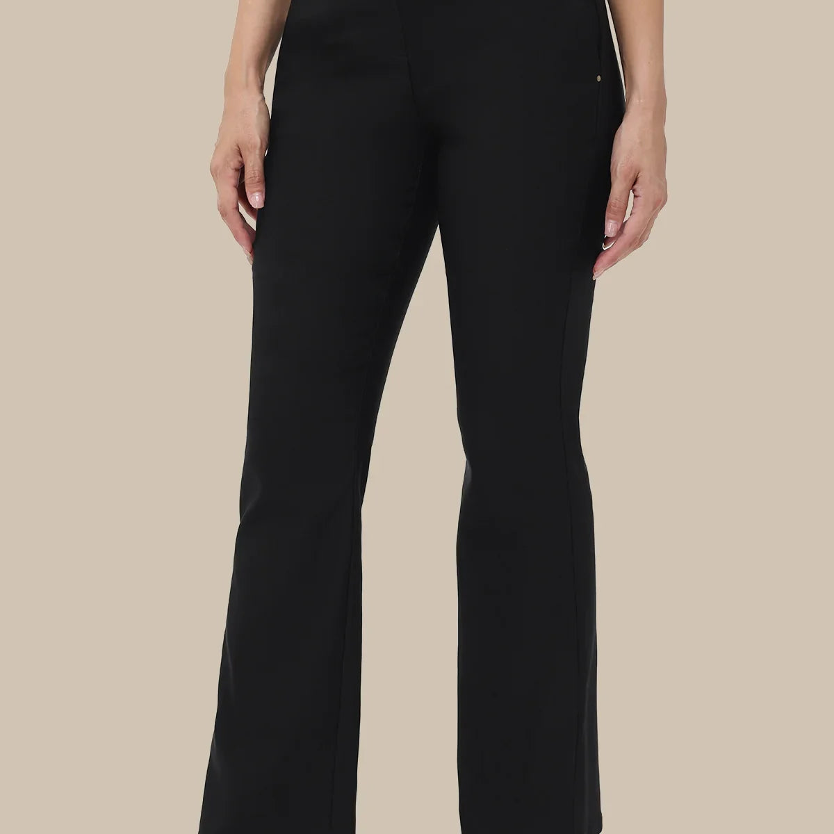A model wearing black wide-leg cropped trousers with a white top and black flats, shown from the waist down against a solid beige background.