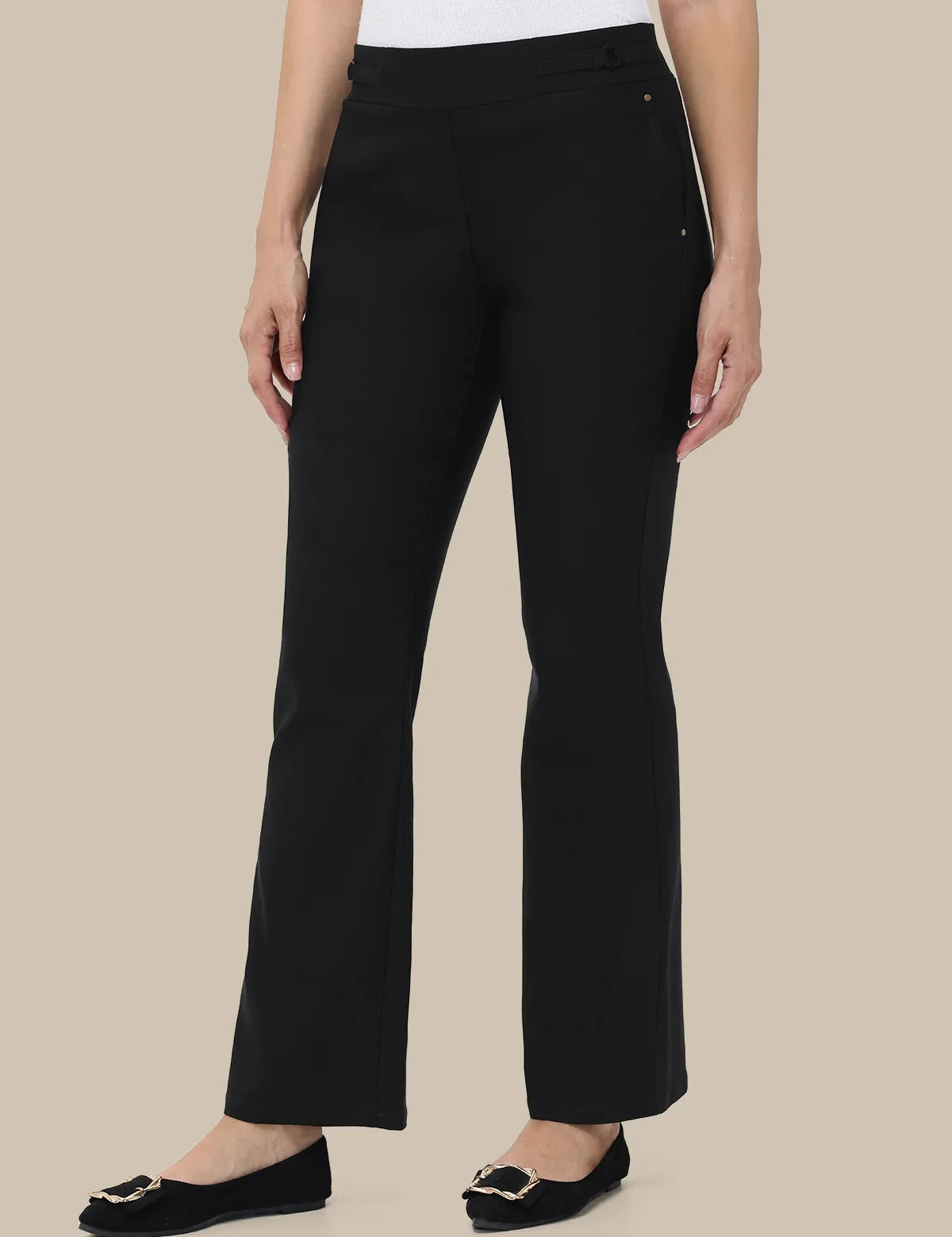A model wearing black wide-leg cropped trousers with a white top and black flats, shown from the waist down against a solid beige background.