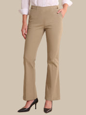 A model wearing a pair of beige straight-leg pants with a white collared shirt and black pointed-toe heels, shown from the waist down against a solid beige background.