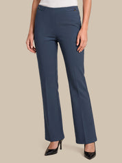 A model wearing a pair of slate blue straight-leg trousers with a white top and black pointed-toe heels, shown from the waist down against a solid beige background.