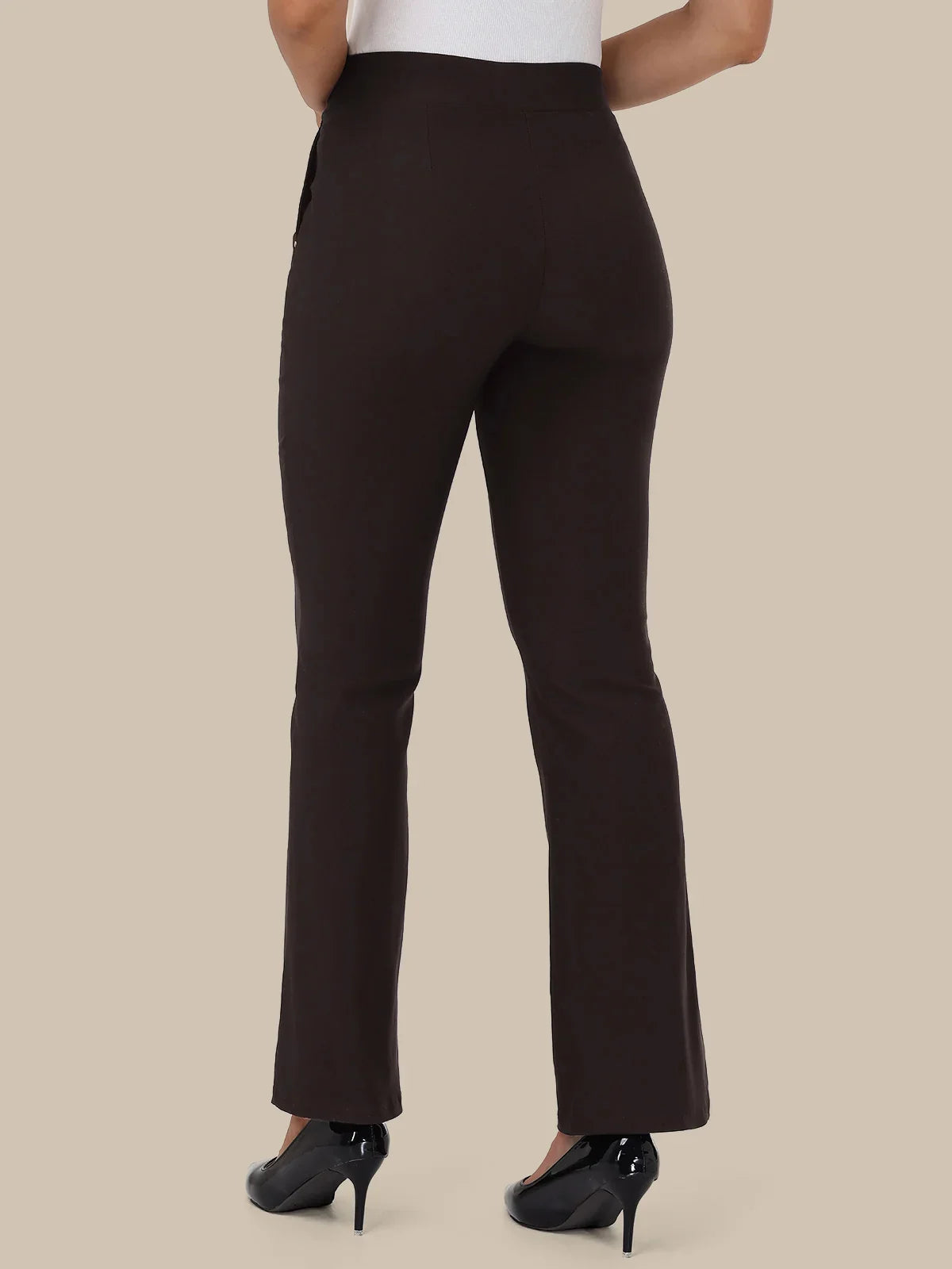 A person shown from the back wearing dark brown high-waisted flared pants with black high heels against a plain beige studio background.