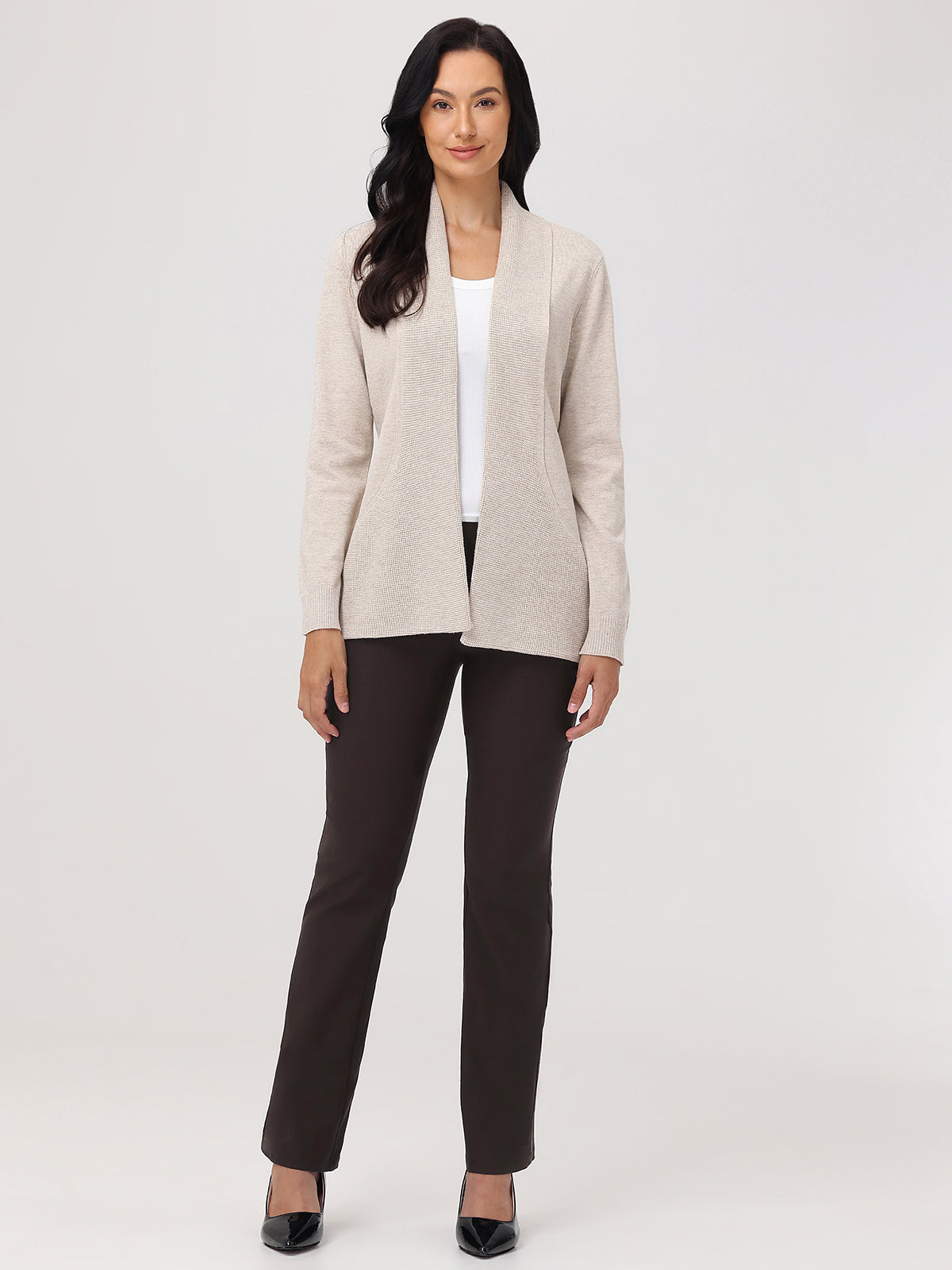 Woman wearing a beige blazer over a white top and brown pants on a white background