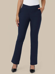 A model wearing navy blue straight-leg trousers with a white top and black pointed-toe heels, standing against a solid beige background.