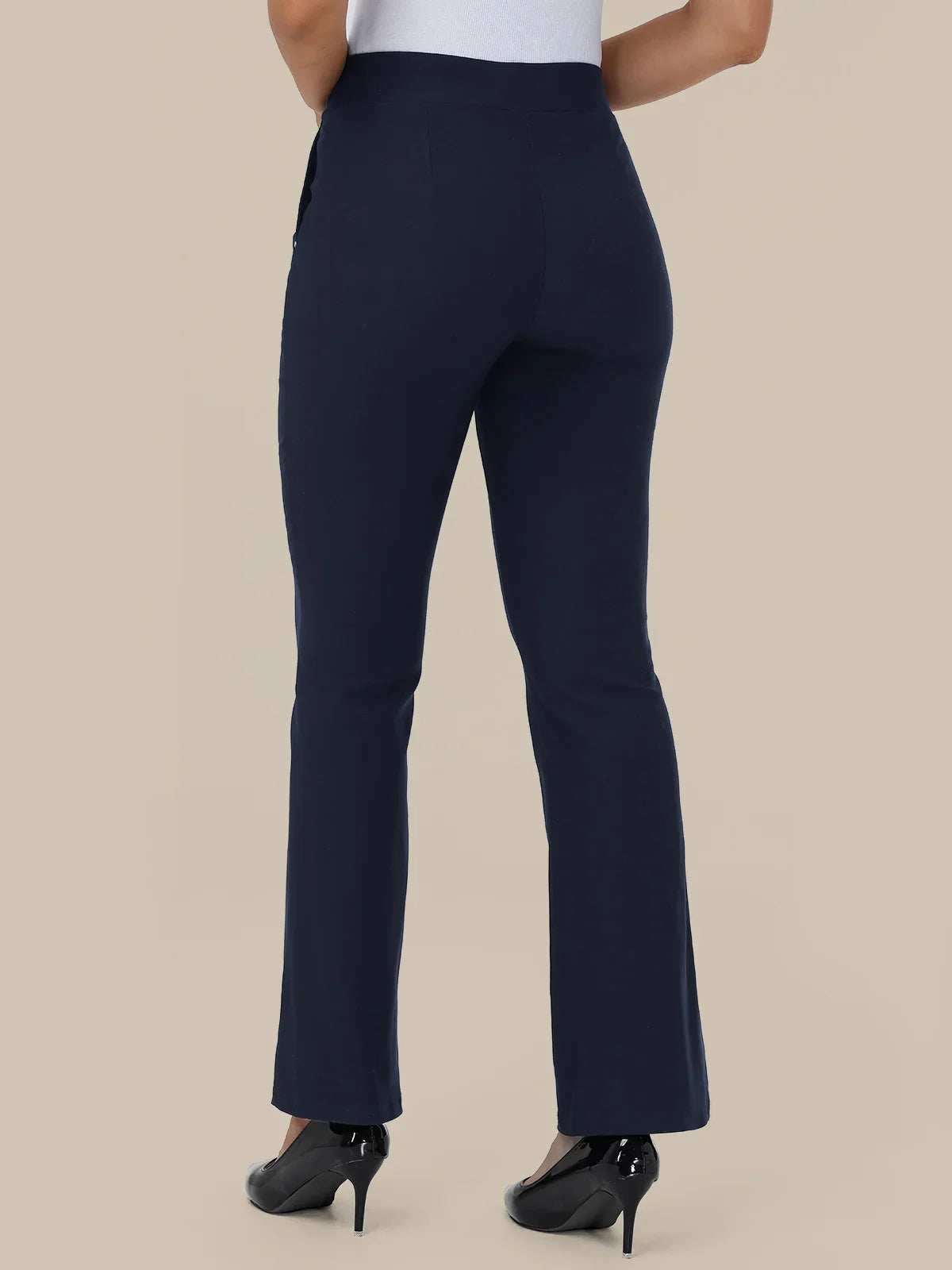 A person shown from the back wearing high-waisted navy blue flared pants with black high heels against a plain beige studio background.
