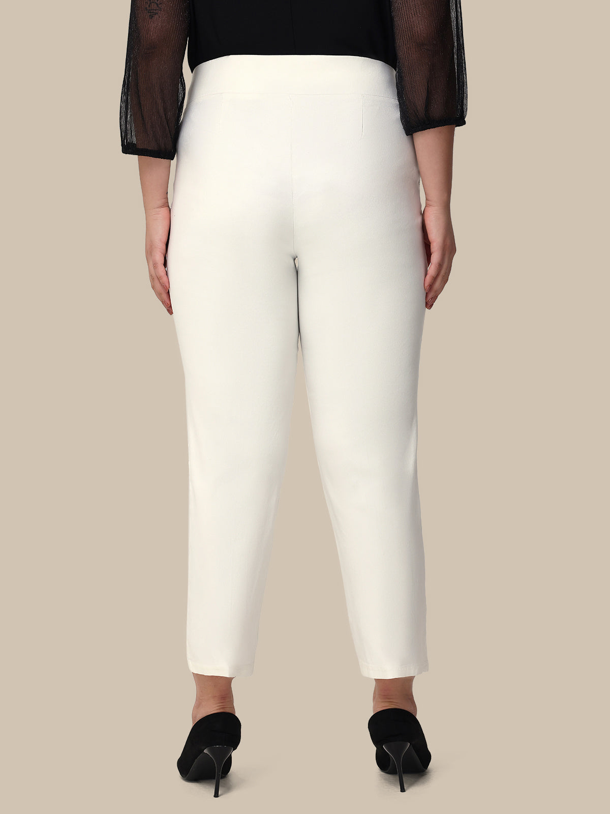 Person wearing white pants with a black top on a beige background