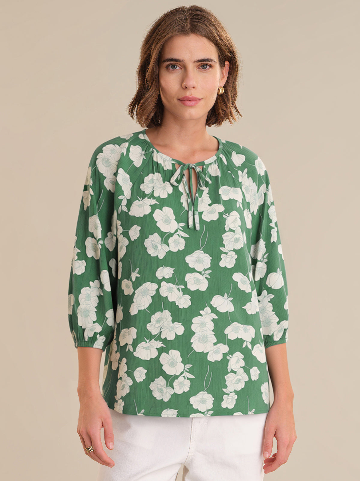 Woman wearing a green floral blouse against a beige background