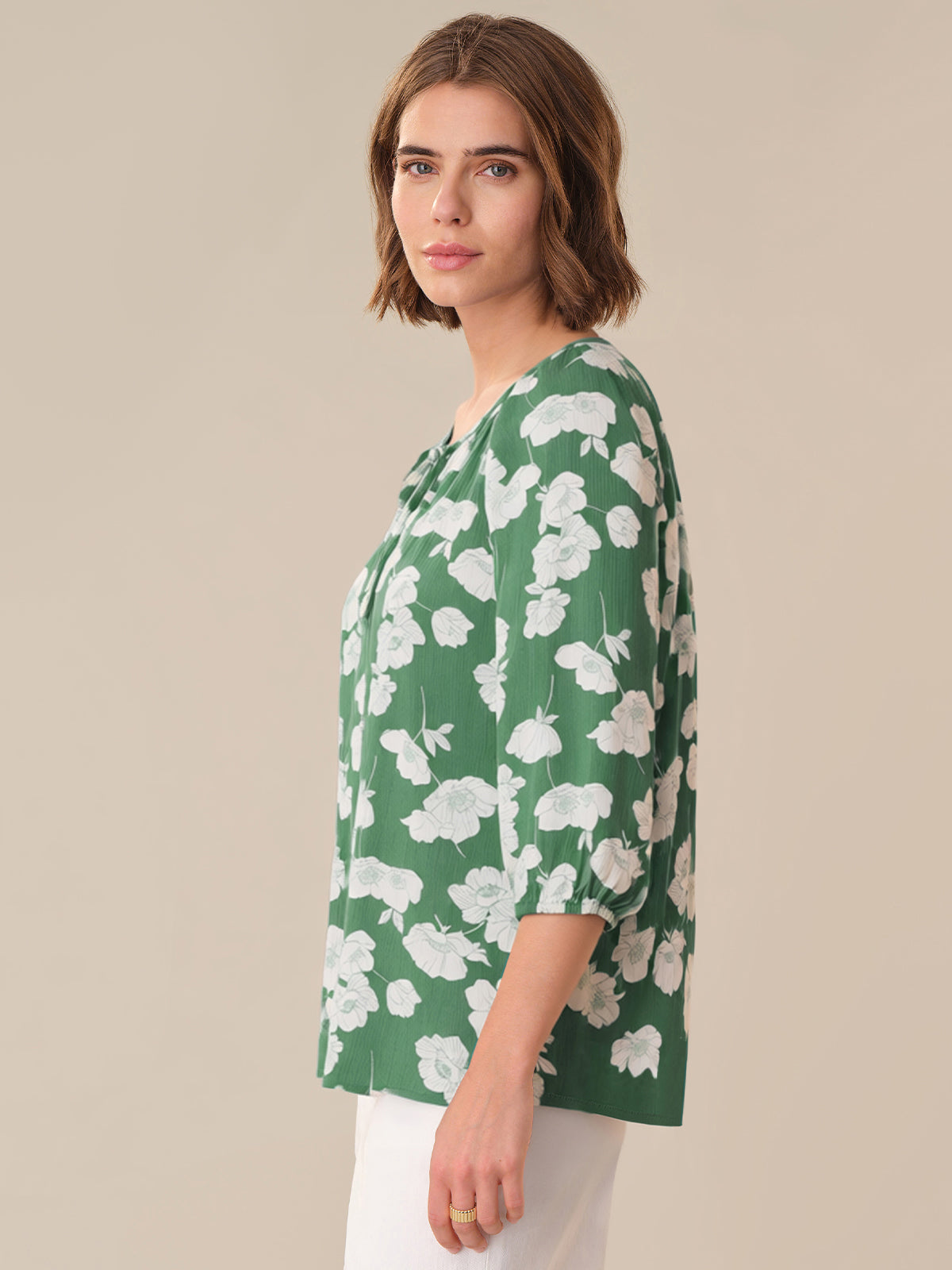 Woman wearing a green floral blouse against a beige background