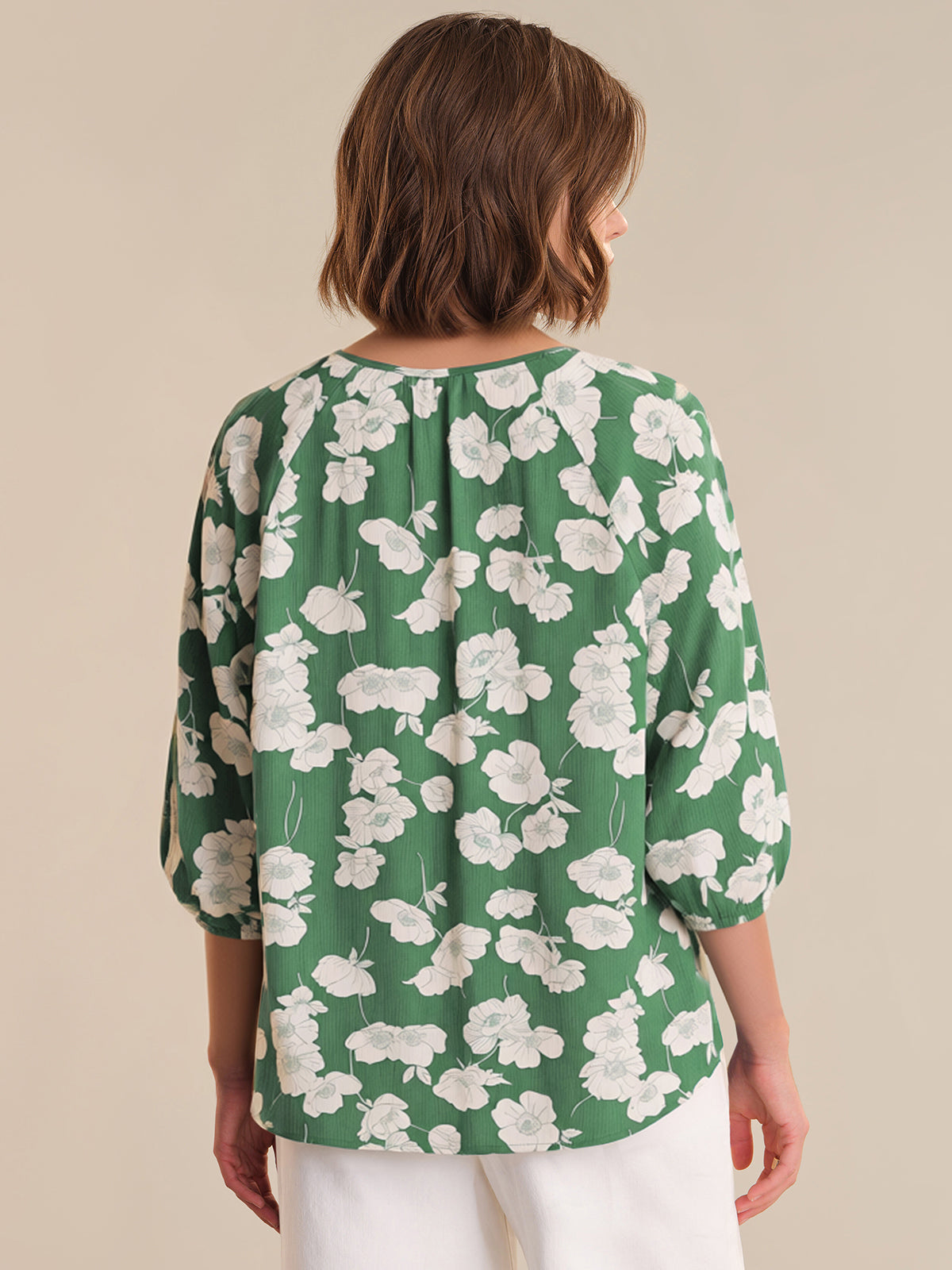Woman wearing a green floral blouse against a beige background