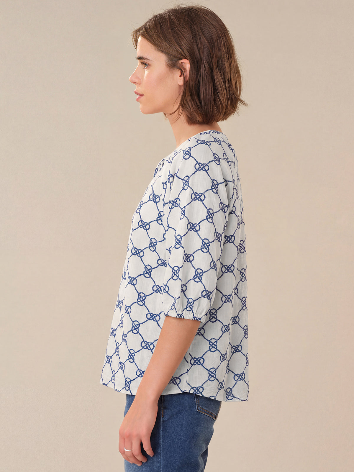 Woman wearing a blue and white patterned shirt against a beige background