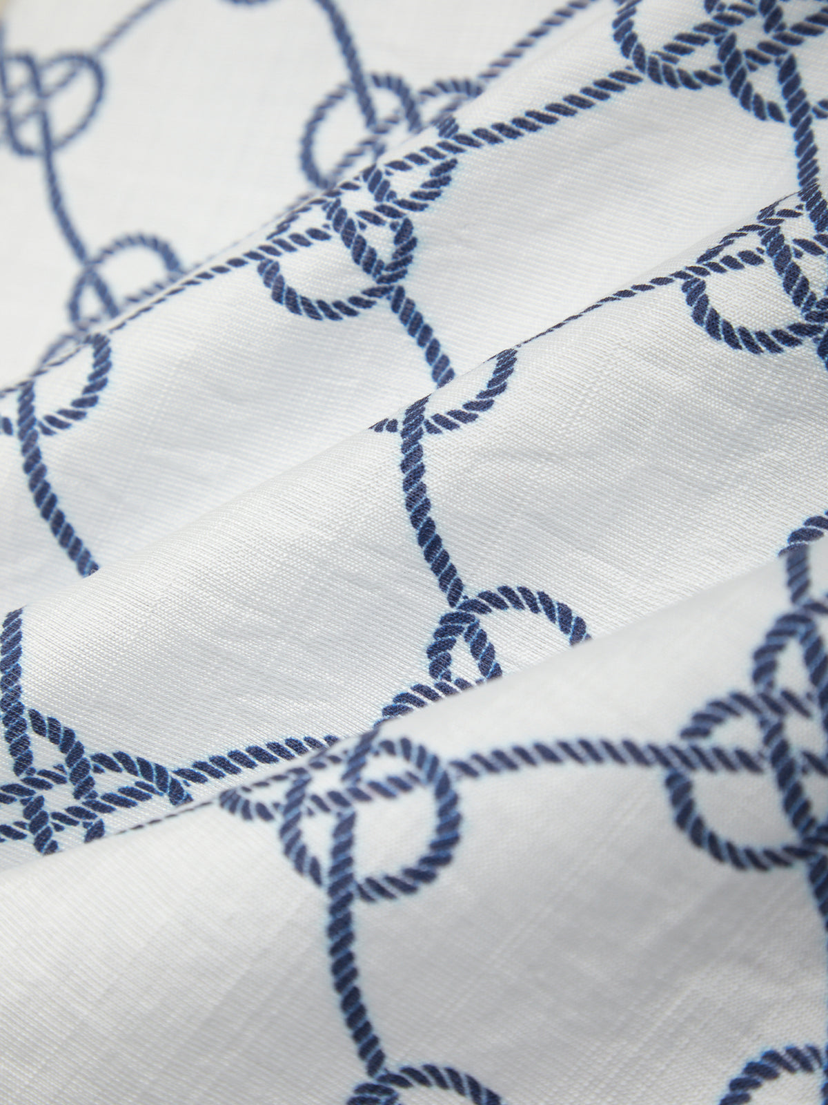 Close-up of white fabric with blue embroidered rope pattern
