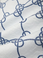 Close-up of white fabric with blue embroidered rope pattern