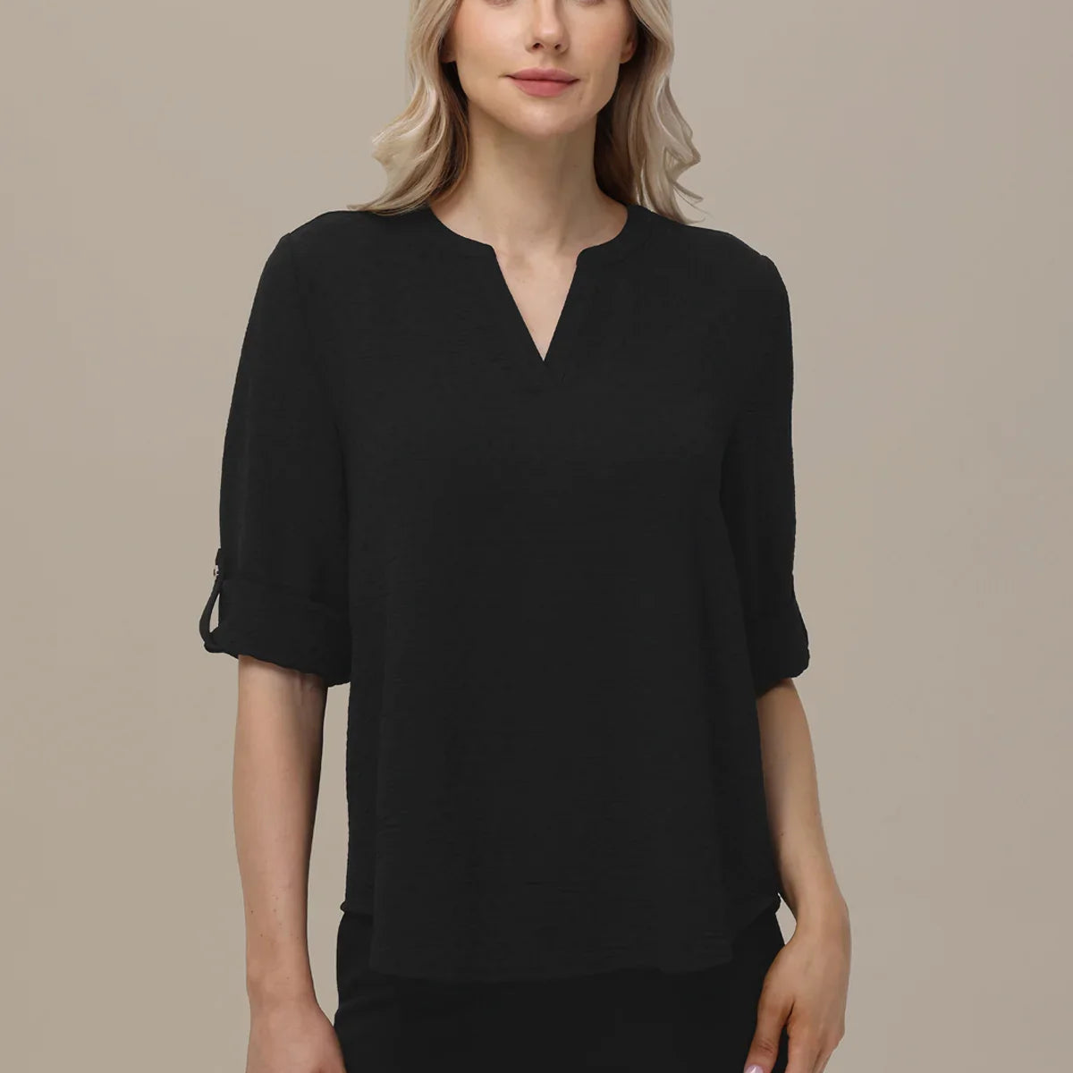 Woman wearing a black blouse against a beige background