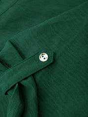 Close-up of a dark green textured fabric garment with a matching fabric tie and a small round metallic button.