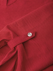 Close-up of a red textured fabric garment with a small silver button detail on a folded cuff or sleeve.
