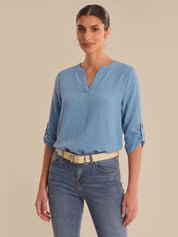 Woman wearing a blue blouse and jeans against a beige background