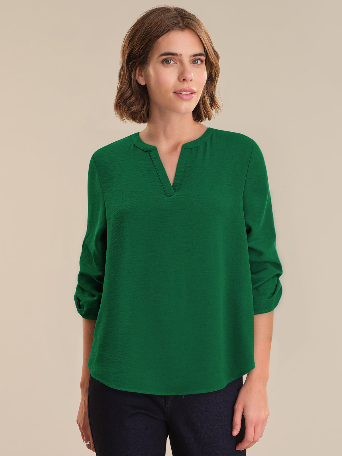 Woman wearing a green blouse against a beige background