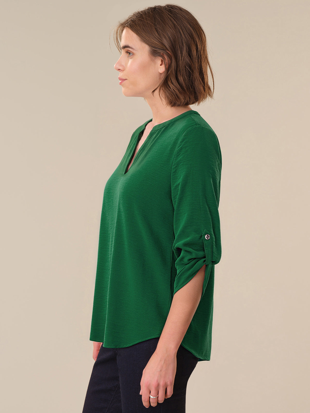 Woman wearing a green blouse against a beige background