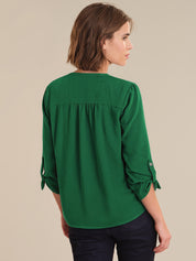 Woman wearing a green blouse with rolled-up sleeves on a beige background