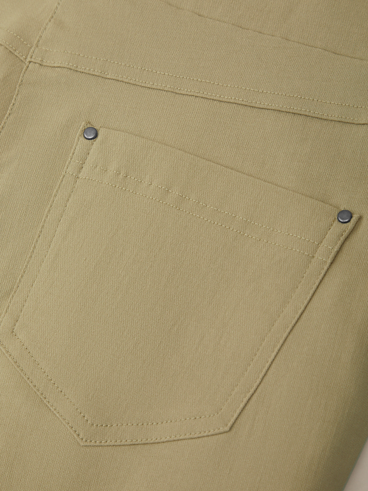 Close-up of a beige pocket on a garment with visible stitching details.