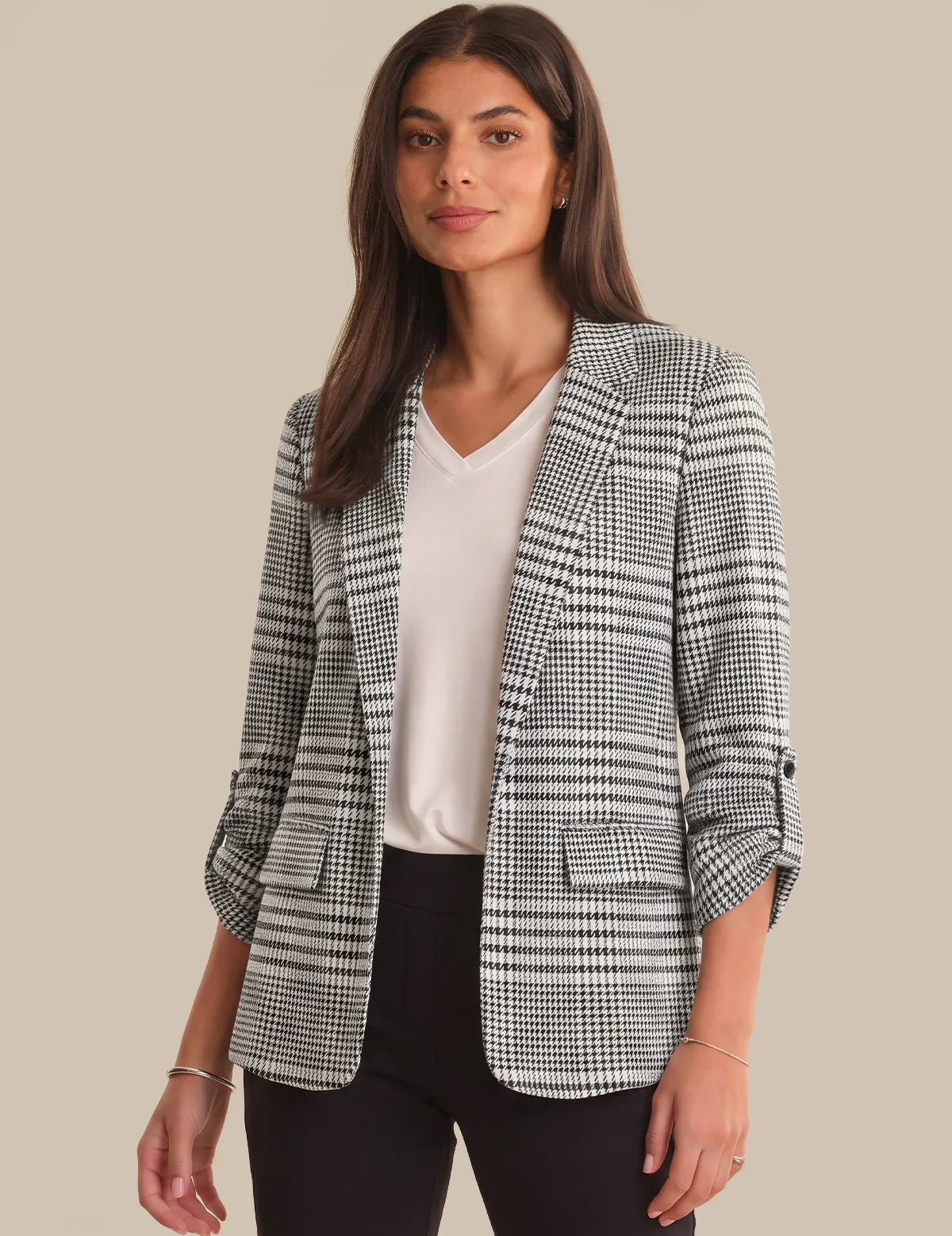 Woman wearing a checkered blazer over a white shirt on a beige background