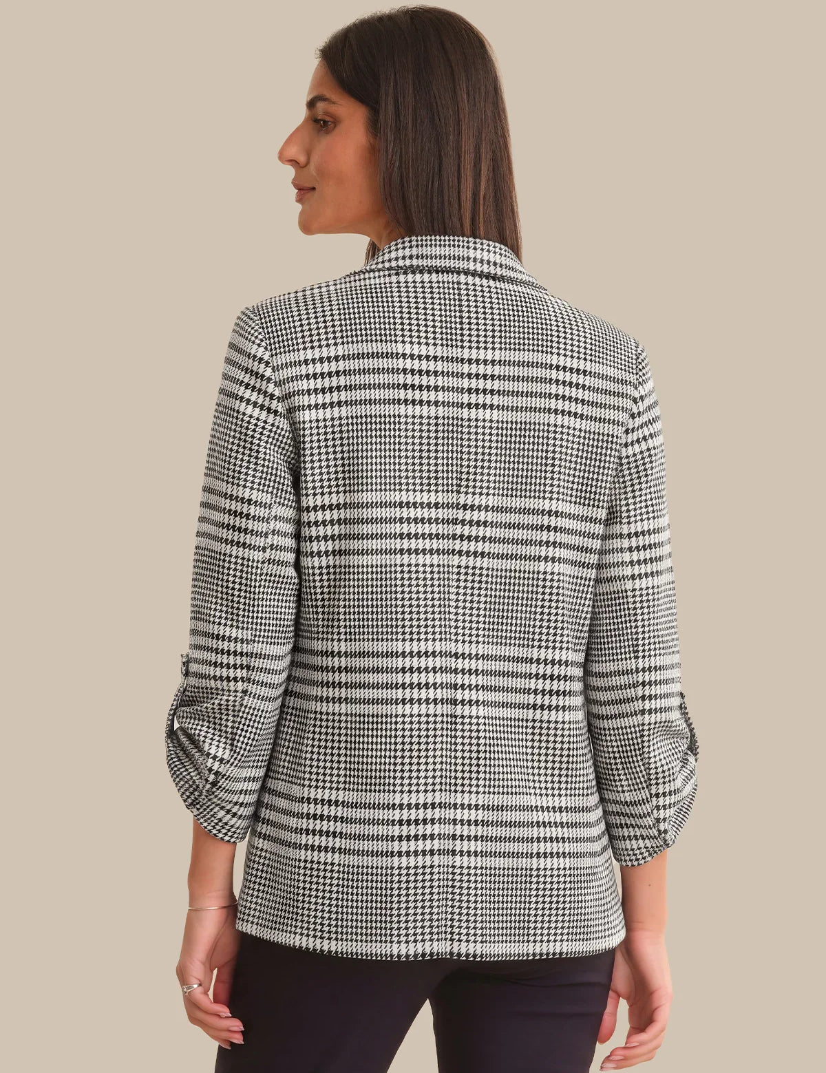 Woman wearing a black and white checkered blazer on a beige background