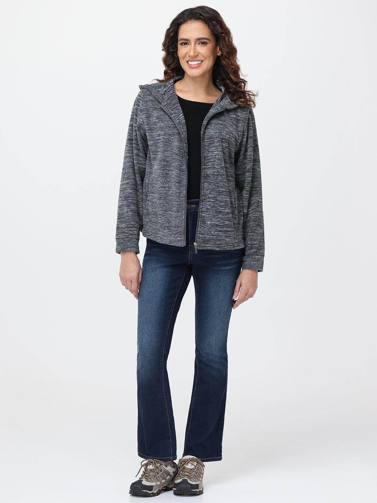 Woman wearing a gray hooded jacket and blue jeans on a white background