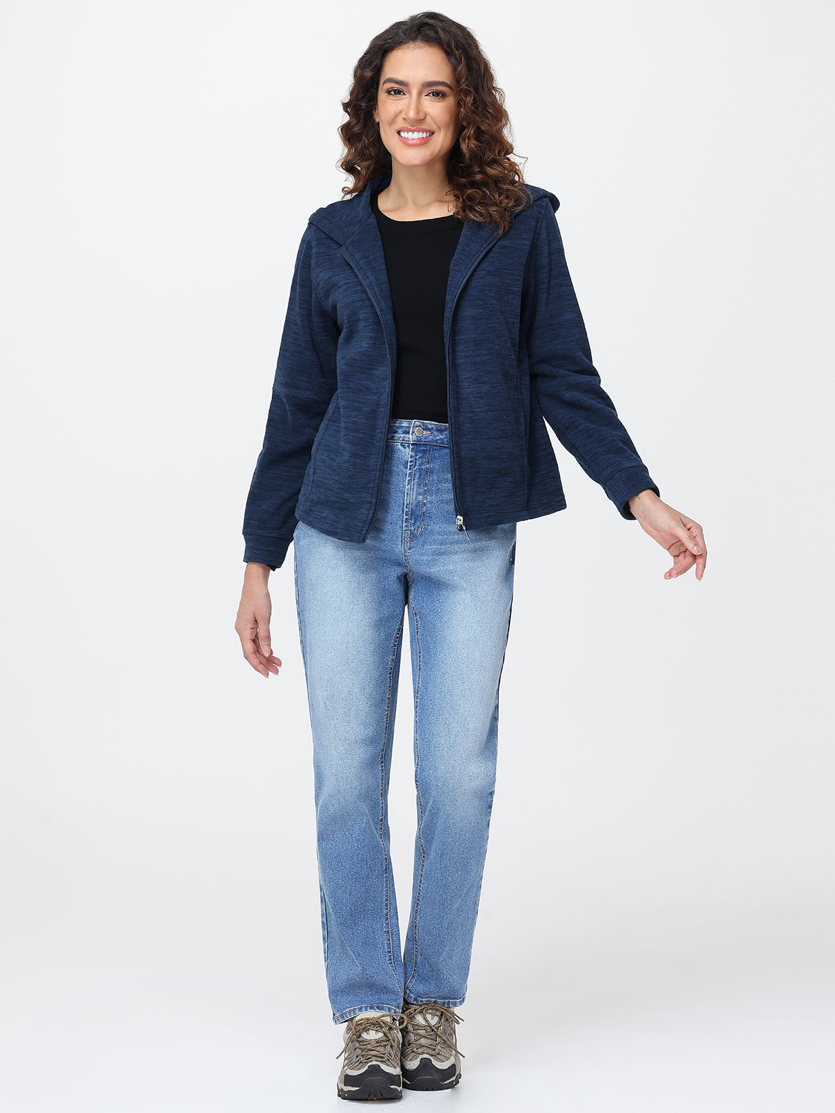 Woman wearing a navy blue jacket and light blue jeans on a white background