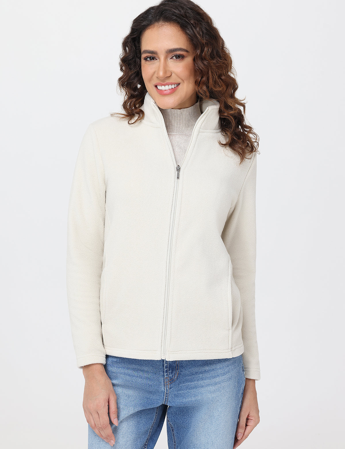 Woman wearing a cream jacket over a gray turtleneck on a white background