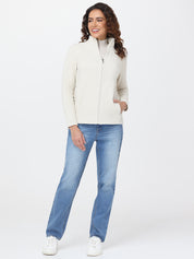 Woman wearing a white puffer jacket, light blue jeans, and white sneakers on a white background