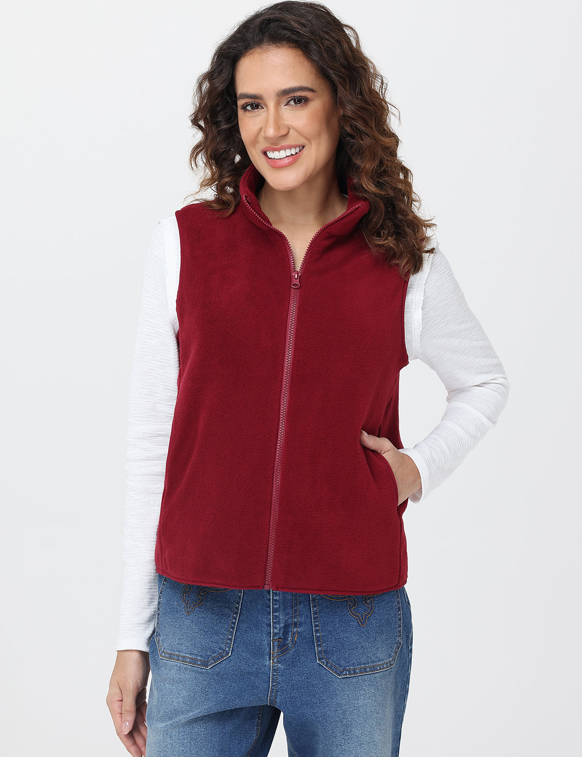 Woman wearing a red fleece vest over a white shirt on a white background