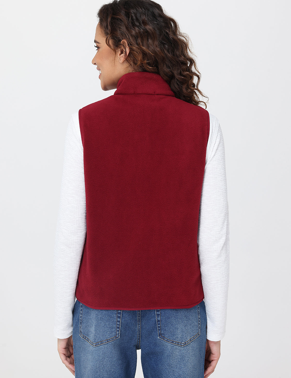 Person wearing a red vest over a white shirt and blue jeans on a light gray background