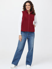 Woman wearing a red vest and blue jeans on a white background