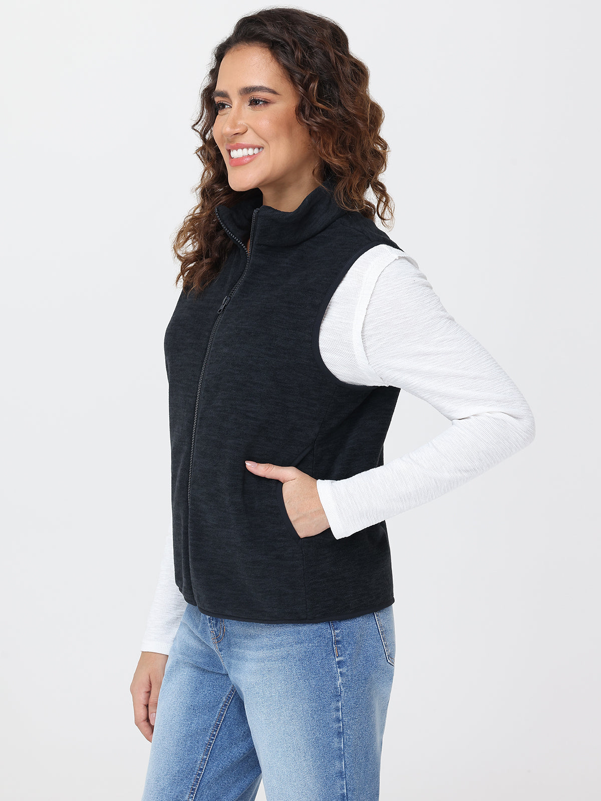 Woman wearing a black vest over a white shirt with blue jeans on a white background