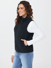Woman wearing a black vest over a white shirt with blue jeans on a white background