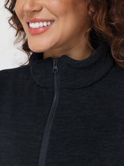Close-up of a person wearing a black zip-up sweatshirt with a blurred background
