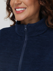 Close-up of a person wearing a navy blue zip-up sweatshirt with a plain background