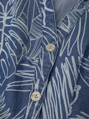 Close-up of a blue shirt with white leaf pattern and button details.